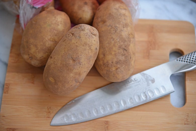 russet potatoes and knife on a cutting board 