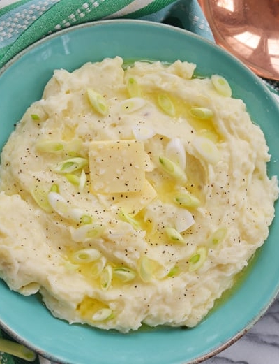 blue bowl of instant pot mashed potatoes with butter and scallions