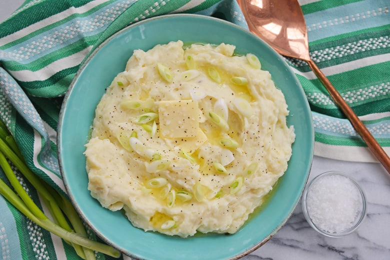 blue bowl of instant pot mashed potatoes with butter and scallions