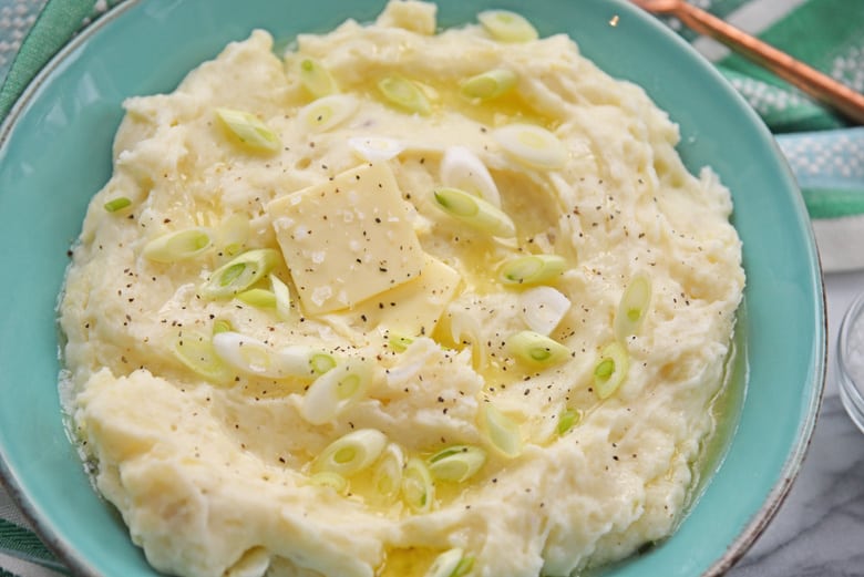 close up of homemade mashed potatoes with butter, salt, pepper and scallions 