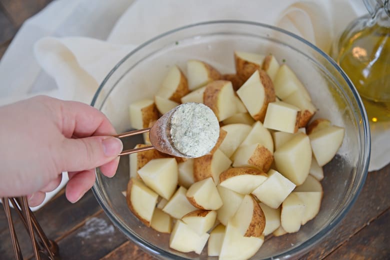 pouring dry ranch seasoning over potatoes