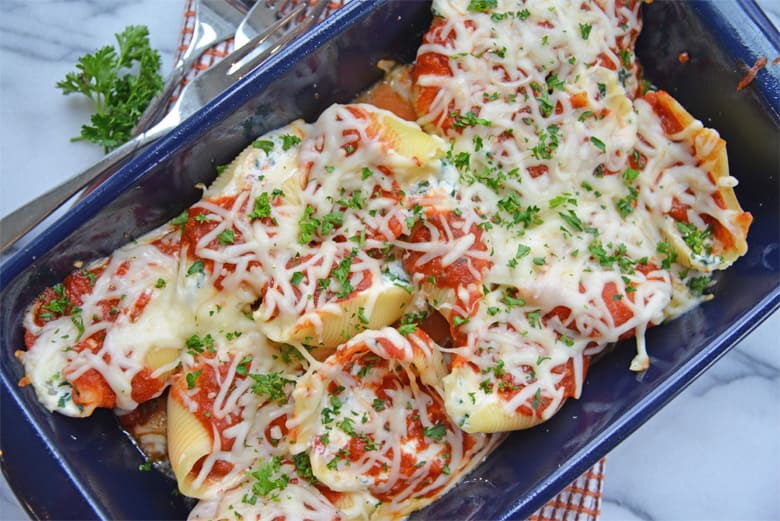 spinach stuffed shells in a blue casserole dish