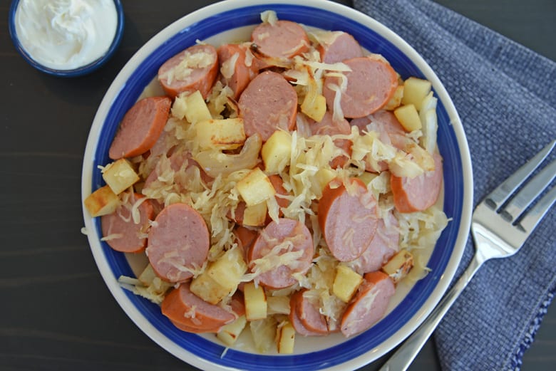 blue serving dish with kielbasa, sauerkraut and onions 