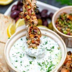 chicken souvlaki skewer dipped into sauce