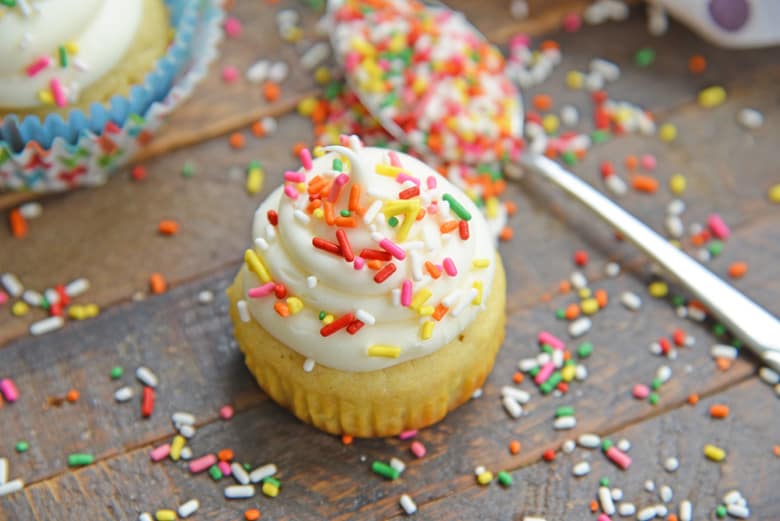 vanilla cupcakes without a wrapper surrounded by sprinkles