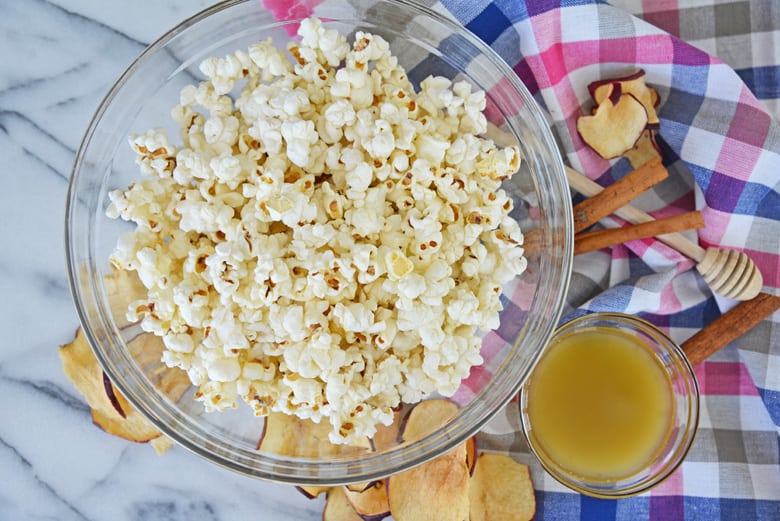 ingredients for apple cinnamon popcorn - popcorn, honey butter, cinnamon and apple chips 