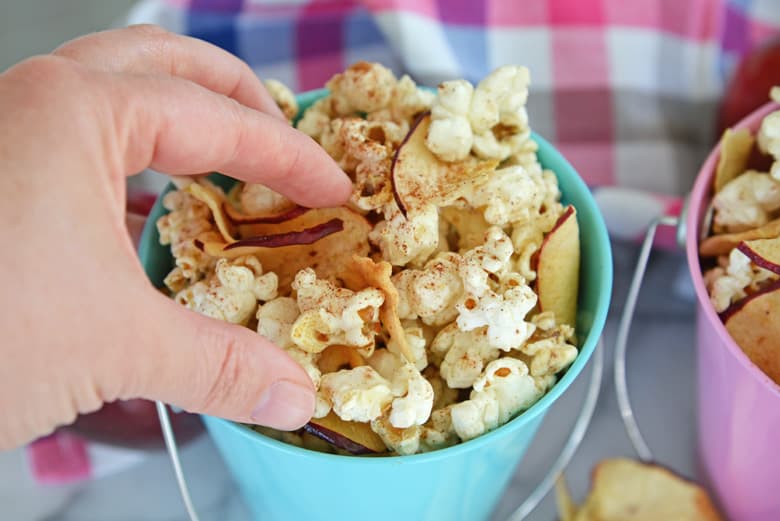 hand reaching into a blue bucket for apple cinnamon popcorn 