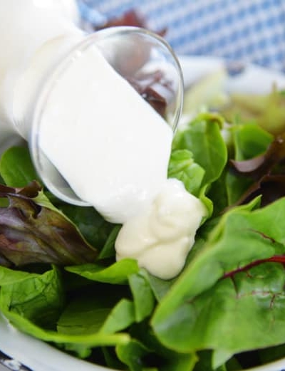 blue cheese dressing pouring over greens