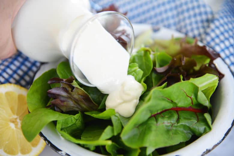 blue cheese dressing pouring over greens