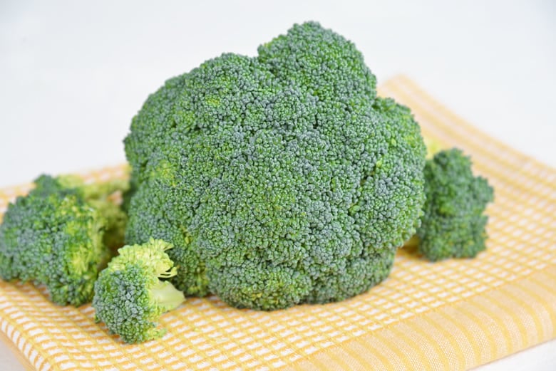 head of broccoli on a yellow linen