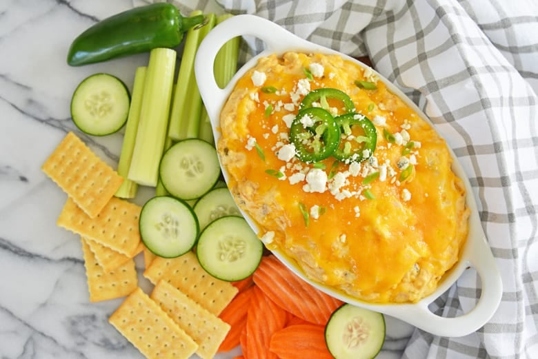 jalapeno buffalo dip with cucumbers, carrots and celery on a marble counter 