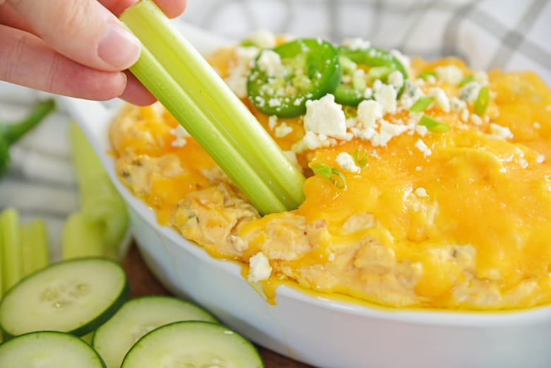 celery dipping into cheesy buffalo wing dip 