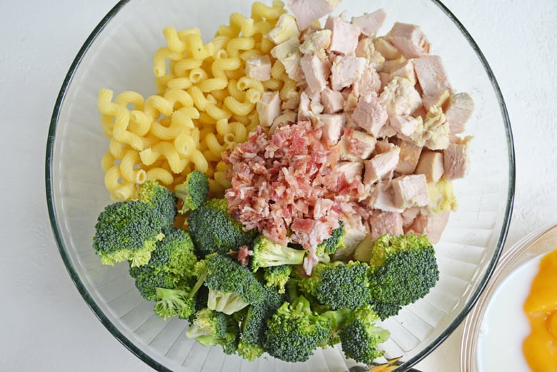 pasta, chicken, bacon and broccoli in a glass mixing bowl  