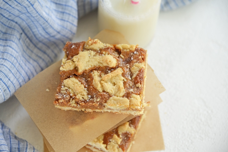 dulce de leche bars stacked between parchment with blue linen 