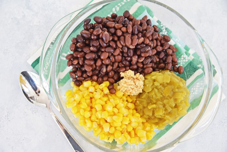 ingredients for black bean salad in a glass mixing bowl 