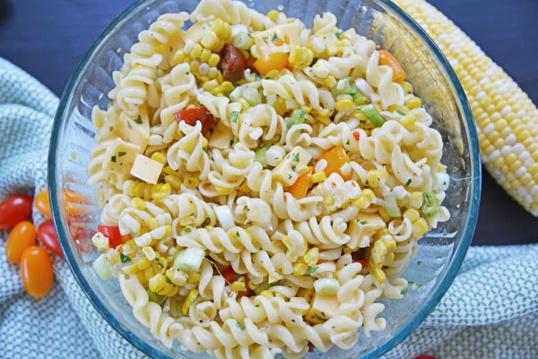 overhead view of gouda and corn pasta salad in a glass mixing bowl 