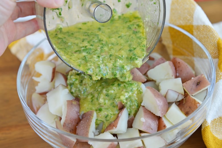 herb dressing pouring over cold red potatoes  