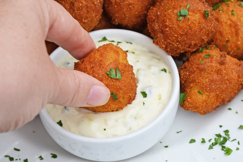 dipping hush puppie into dipping saucec