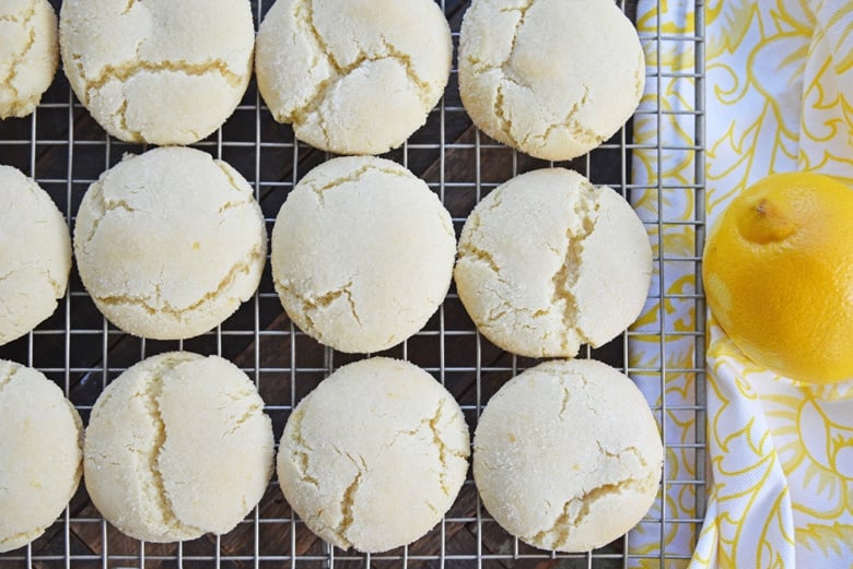 lined up sugar cookies on a cooling rack with a fresh lemon 