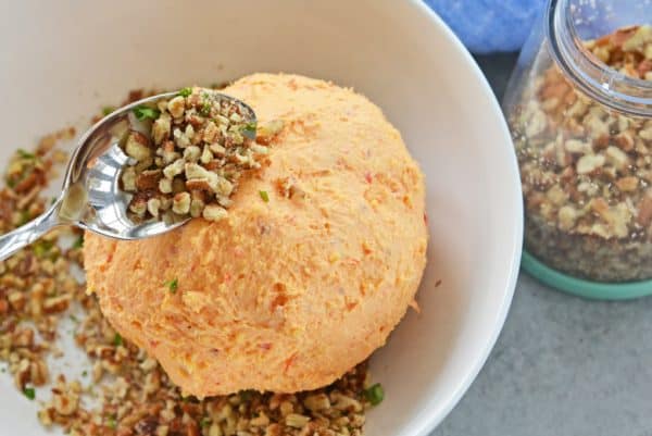 sprinkling walnuts on pimento cheese ball