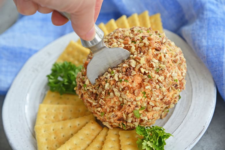 cheese knife cutting into a party cheese ball 