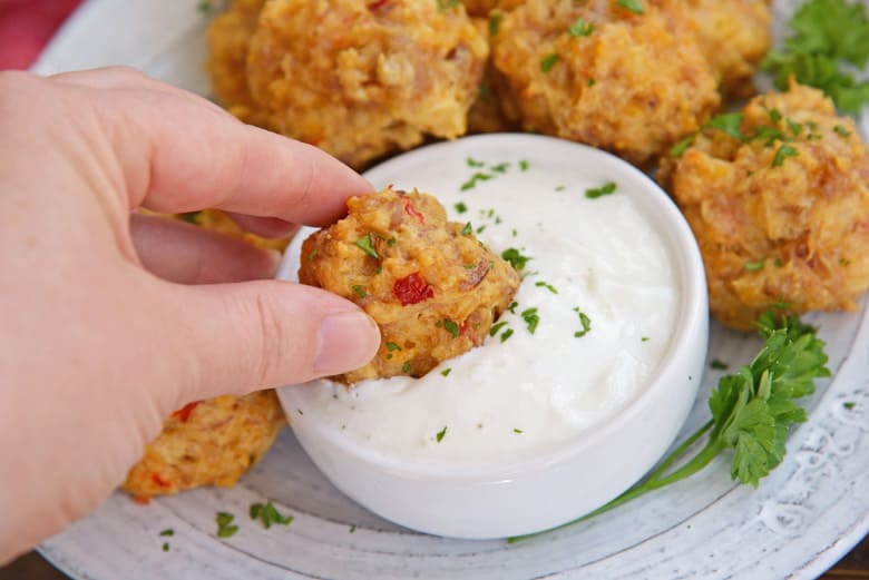 dipping a pimento sausage ball in aioli sauce 