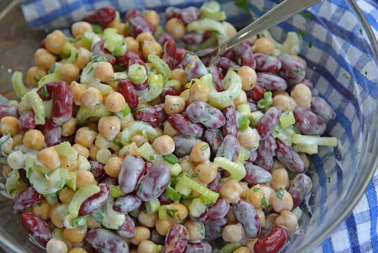 mixing beans together with yogurt, scallions and celery 