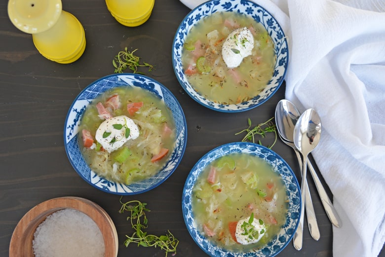 three bowls of pork and sauerkraut soup with garnishes 