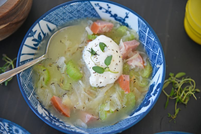 spoon dipping into kielbasa and sauerkraut soup 