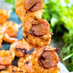 hand holding sausage and shrimp kabobs