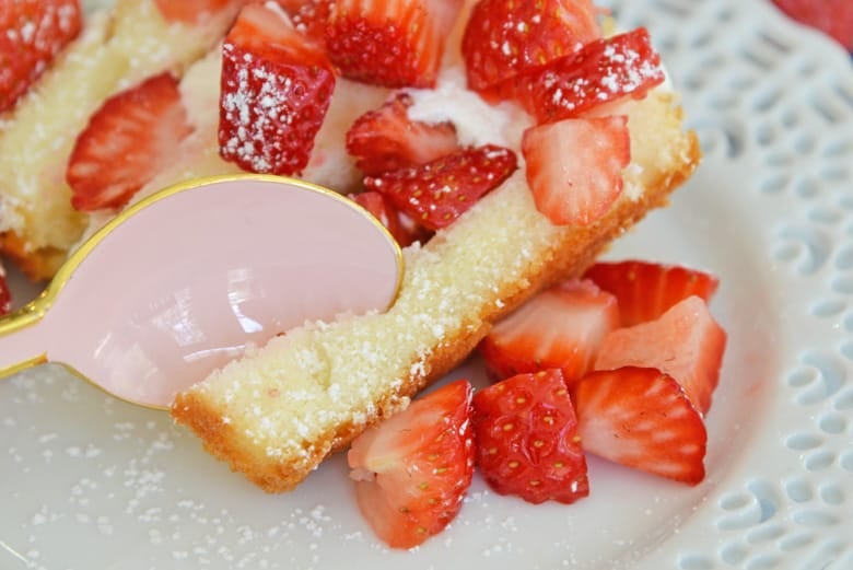 pink spoon digging into strawberry shortcake cake 