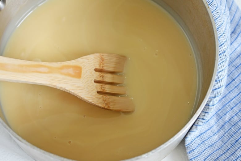 angled shot of wooden spoon in pot of sweetened condensed milk