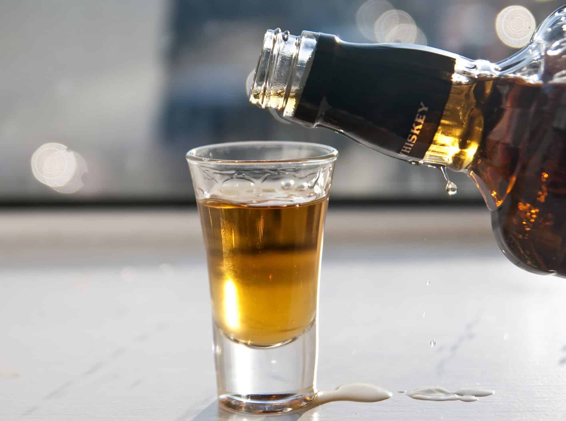 whiskey pouring into a shot glass 