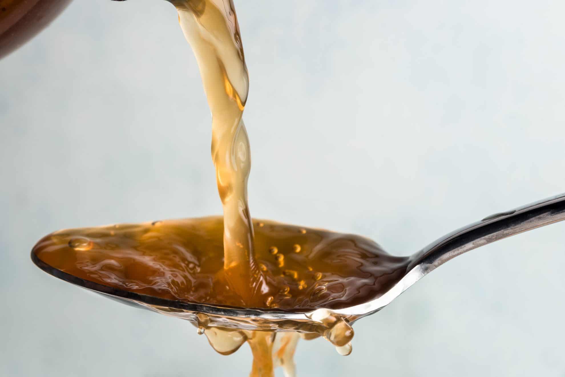 apple cider vinegar pouring into a spoon 