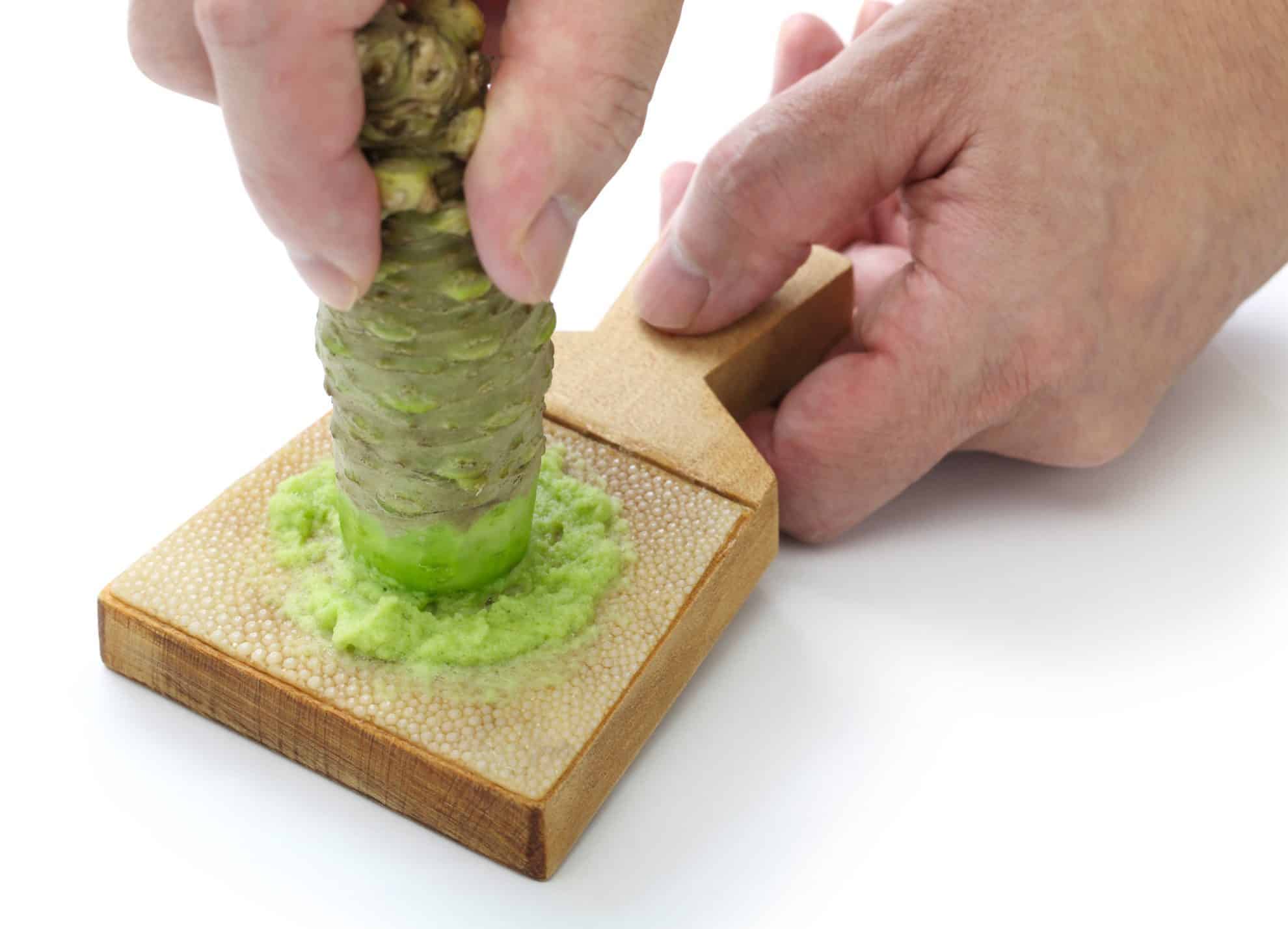 wasabi root being grate on a shark skin grater 