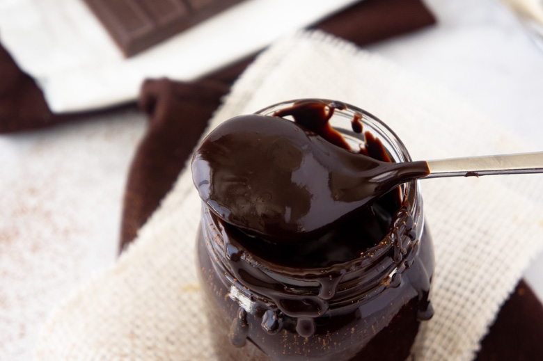 spoon with homemade fudge sauce on a mason jar  