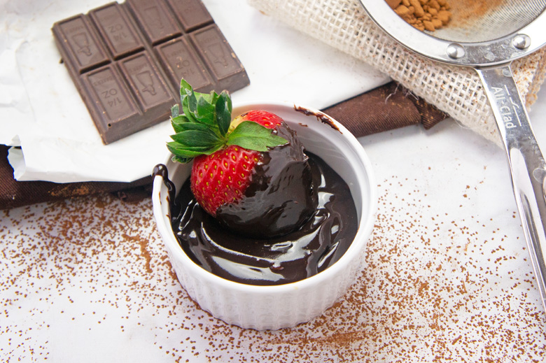 strawberry dipping into fudge sauce in a small white ramekin 