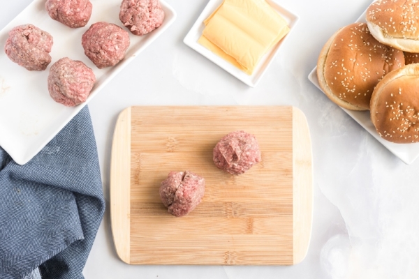 two balls of burger meat on butting board