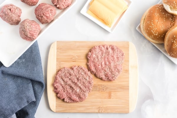 two burger patties on cutting board