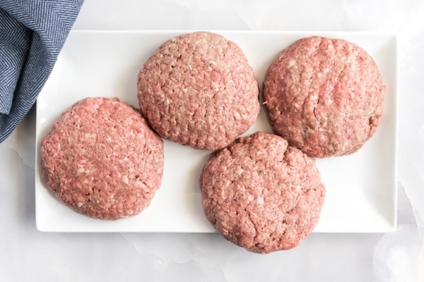 four burger patties on white tray