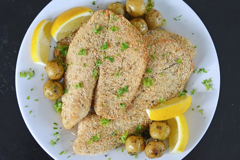 overhead of parmesan tilapia with lemon wedges 