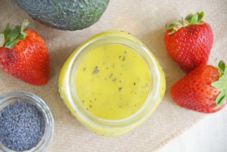 overhead of poppy seed dressing with fresh strawberries, avocado and poppy seeds 