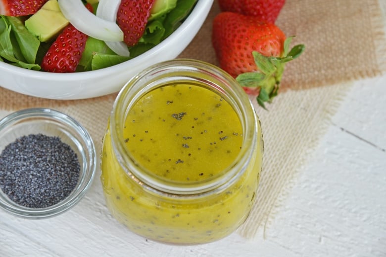 angle view of poppy seed dressing with strawberry salad in the background 
