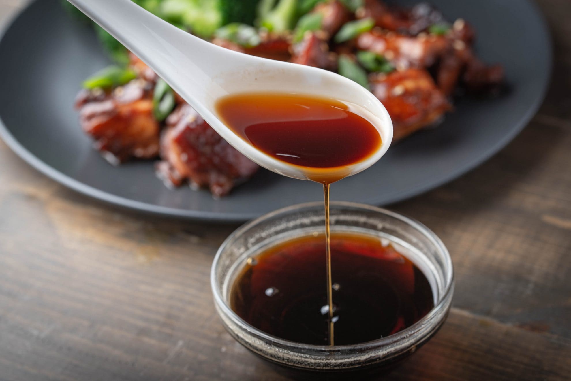spooning soy sauce out of a small glass bowl