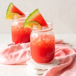 vodka watermelon cocktails in mason jars with fresh watermelon wedge garnish
