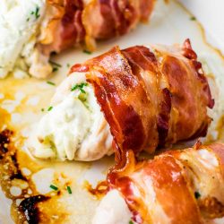 bacon wrapped cream cheese stuffed chicken in a baking dish