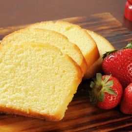 slices of pound cake with fresh strawberries on a wood cutting board