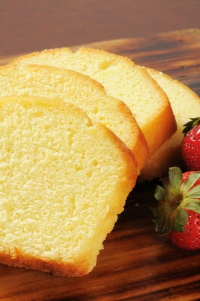 slices of pound cake with fresh strawberries on a wood cutting board