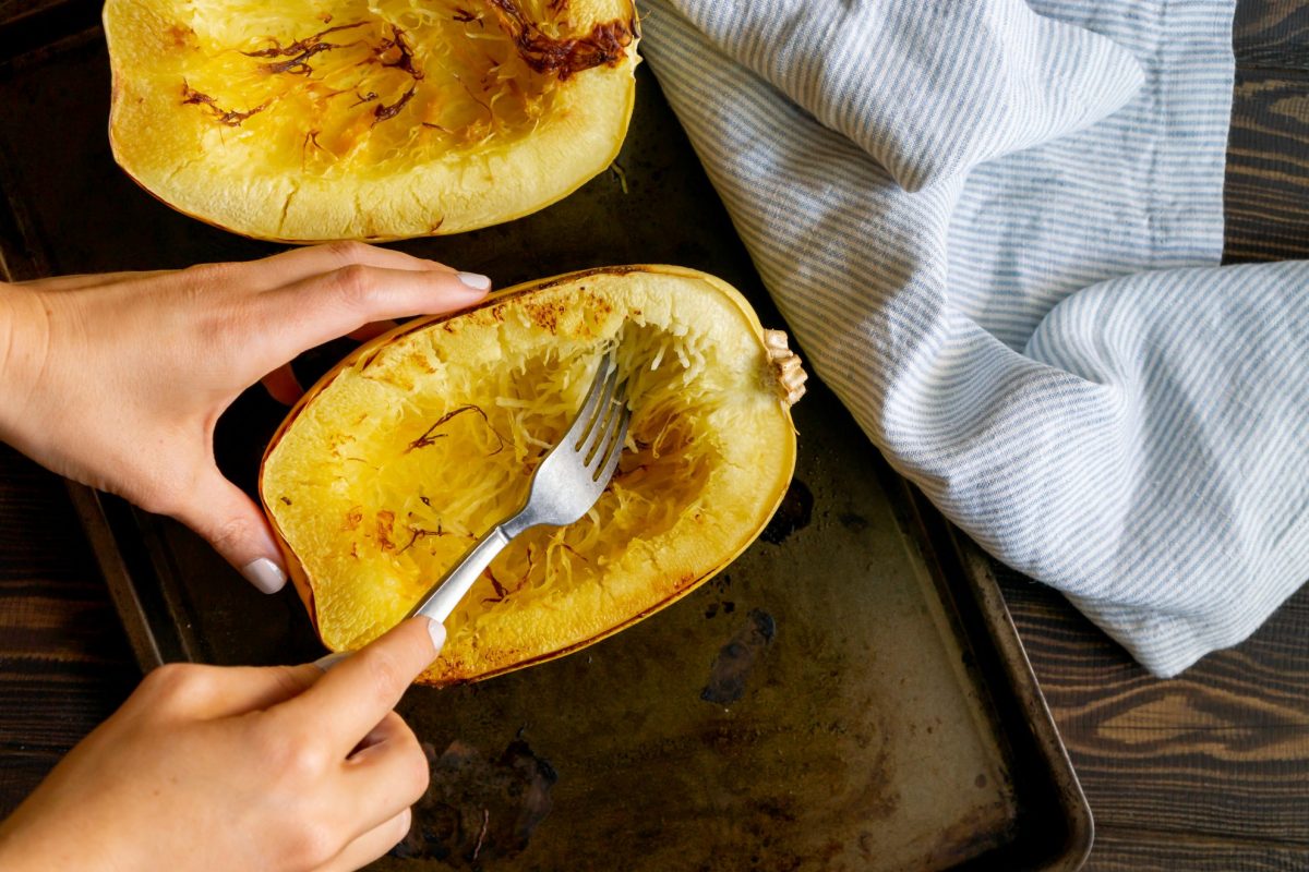 scraping out spaghetti squash on a baking sheet  