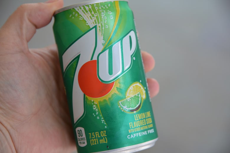 small can of 7 up being held